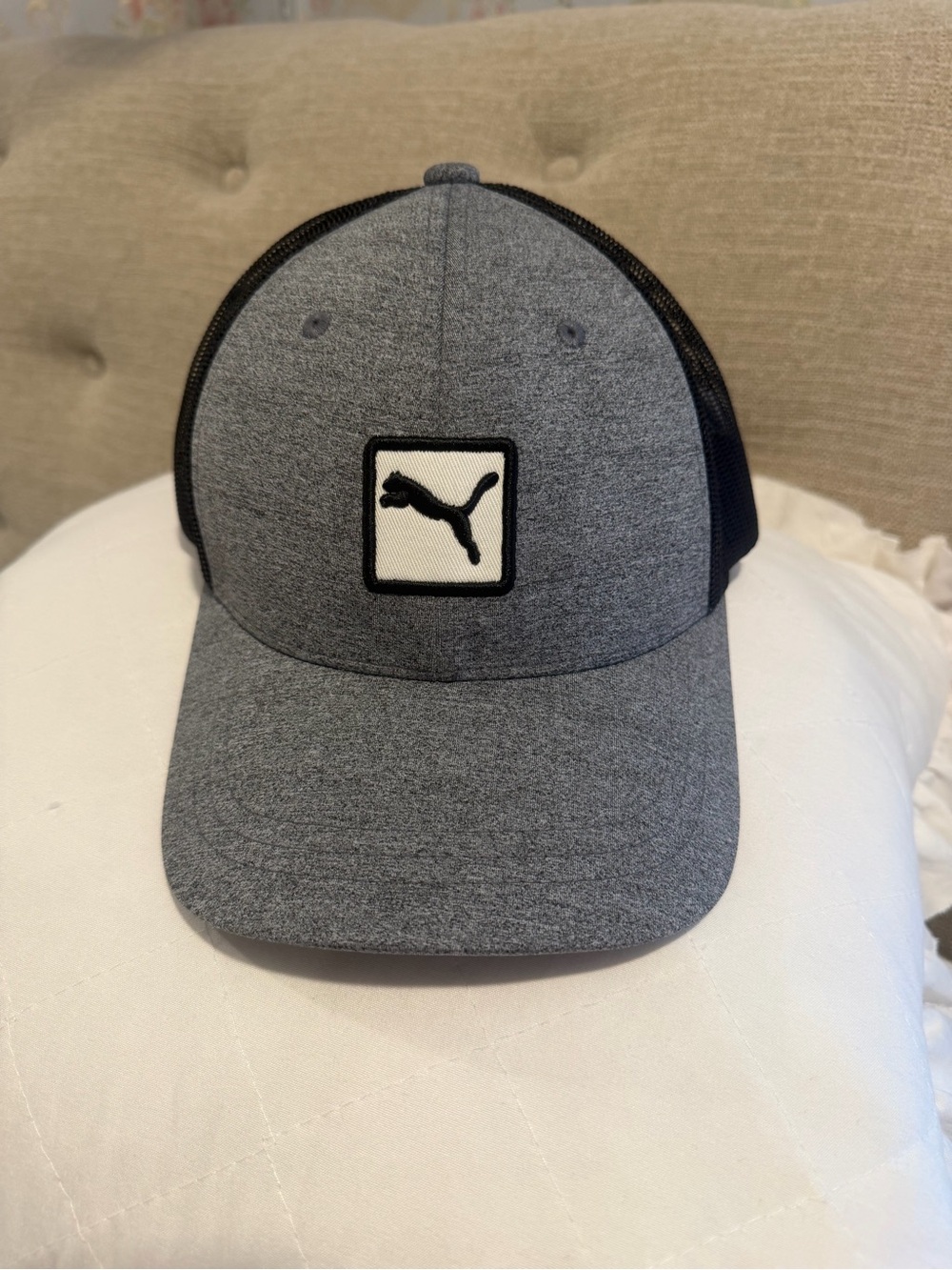 Puma Unisex Retro Trucker Cap features a grey marl front panel and a black mesh